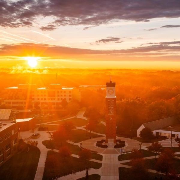 A golden sunrise highlights a university campus in fall.