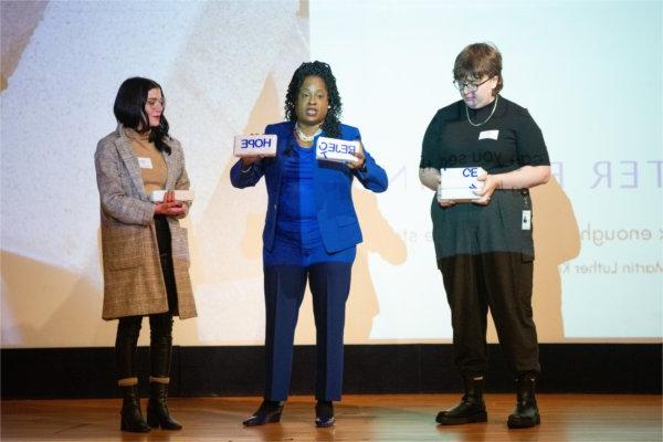 TaRita Johnson interacts with two volunteers on stage during her address for MLK Week