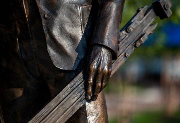 A detail image of a bronze 雕塑 shows a hand holding a piece of art equipment.