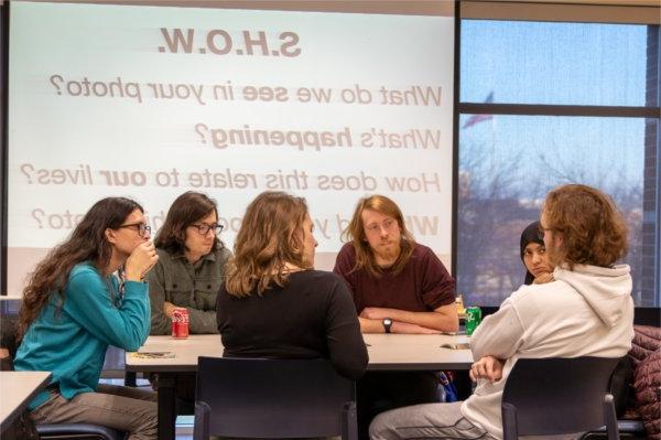 four students at table with projection in background, SHOW, what do we see in your photo? and other questions